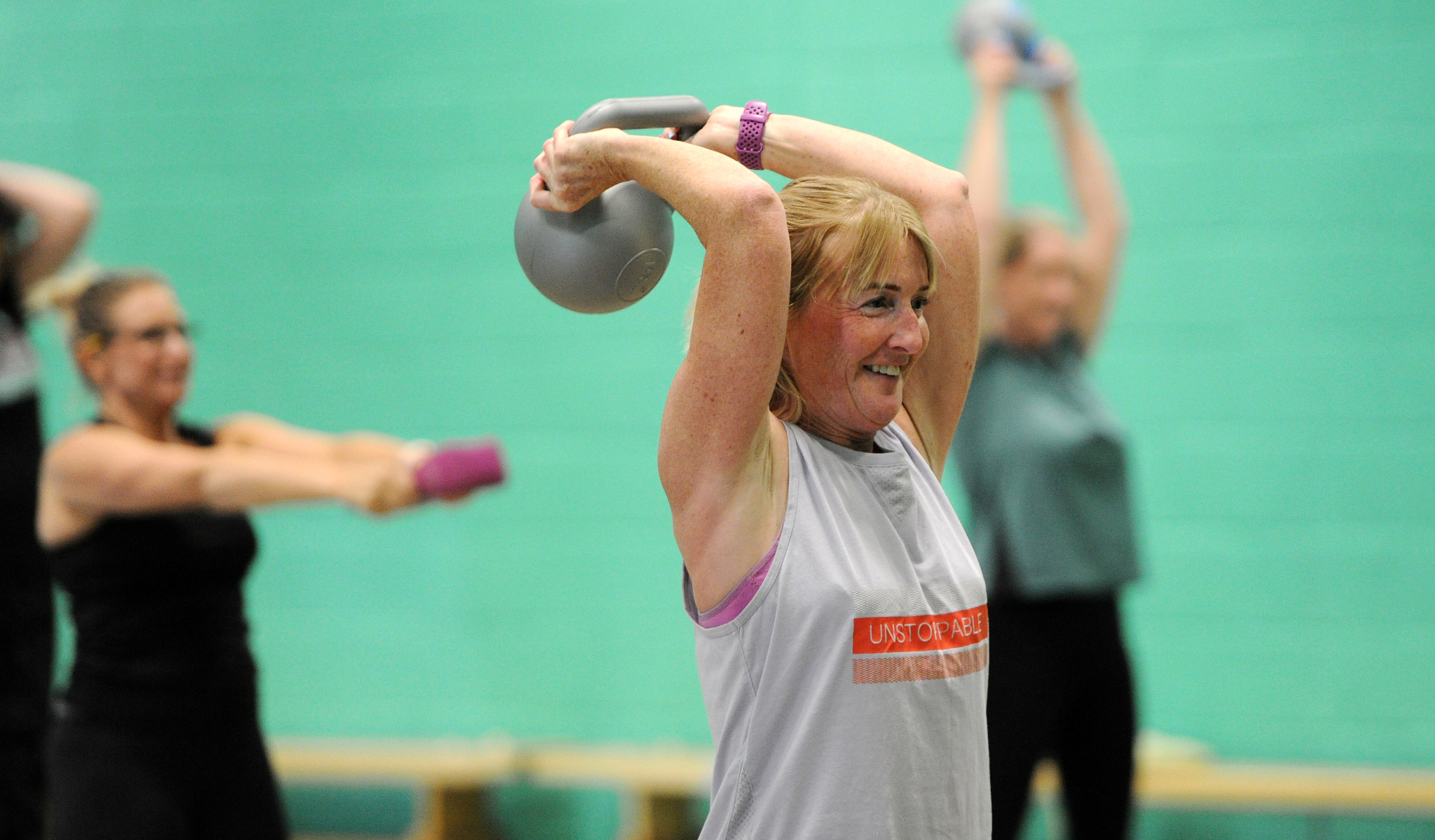 Fitness class with participants lifting weights